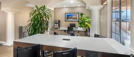 A conference room with a large white table, black chairs, a ceiling fan, and potted plants.