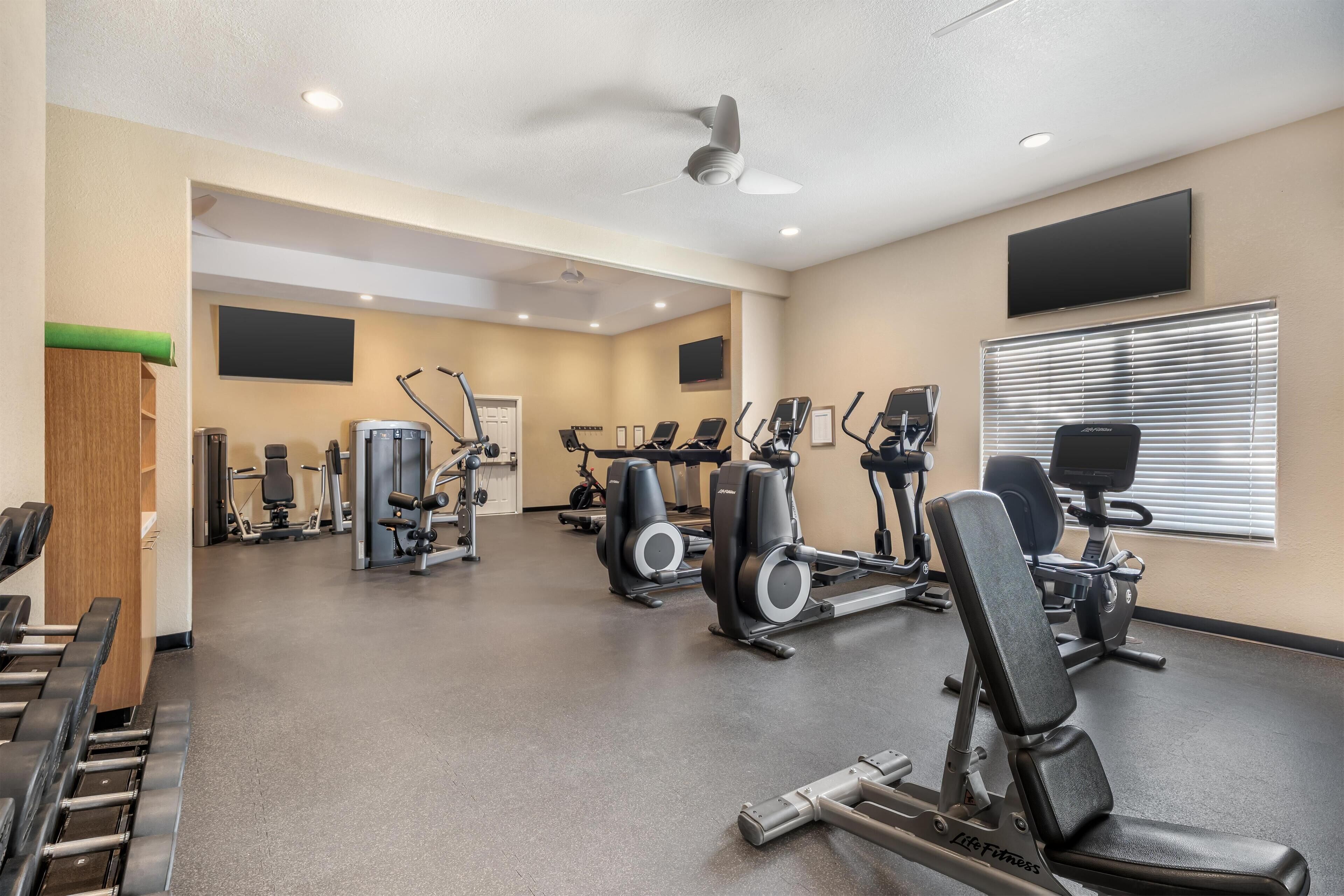 Uma academia com diversos equipamentos de exercício, incluindo esteiras, bicicletas ergométricas e aparelhos de musculação.