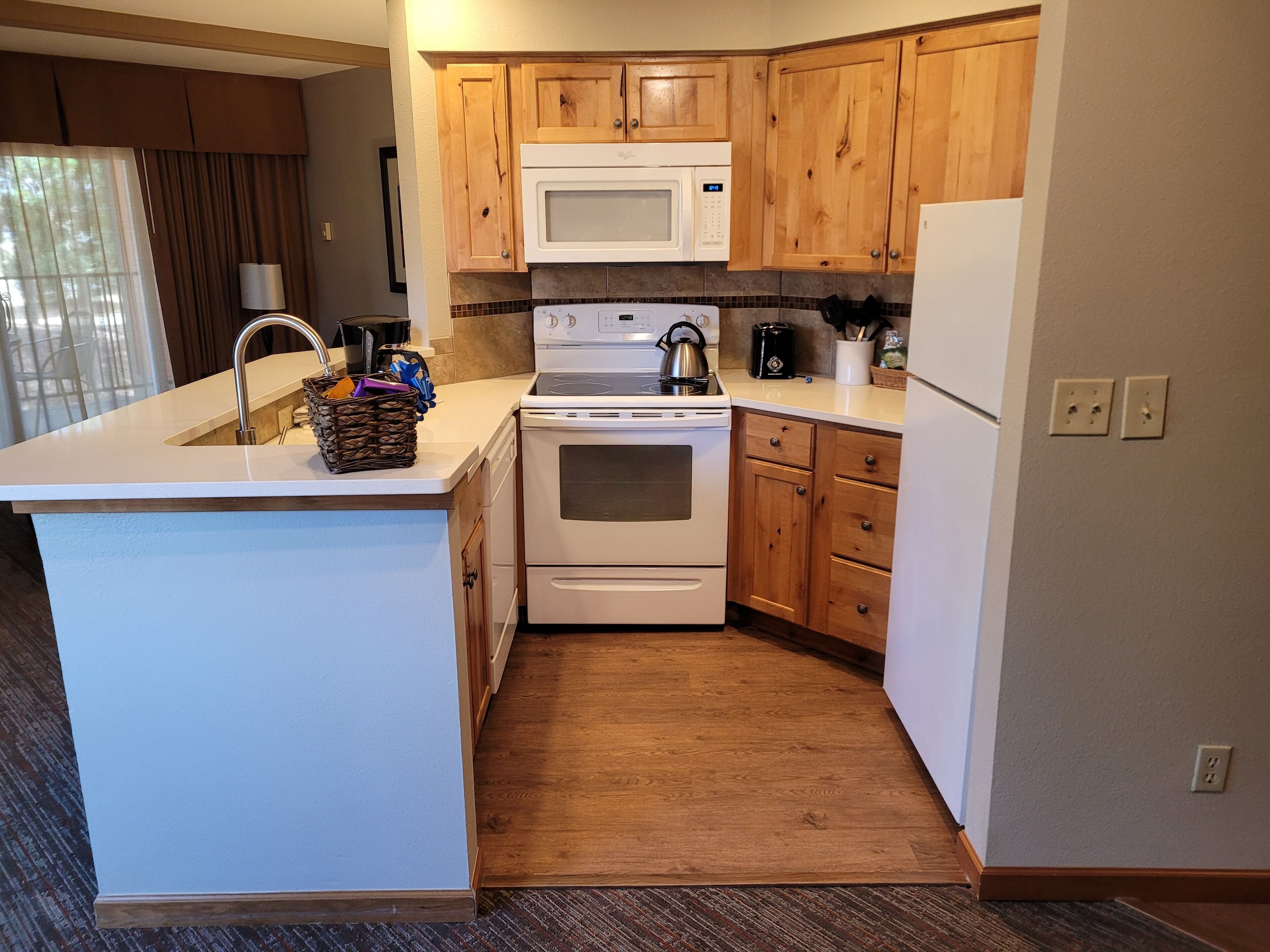 A compact kitchen with wooden cabinets, a built-in microwave, a stove, and a refrigerator.