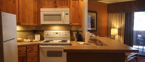 A kitchen with wooden cabinets, a microwave, stove, and a sink.