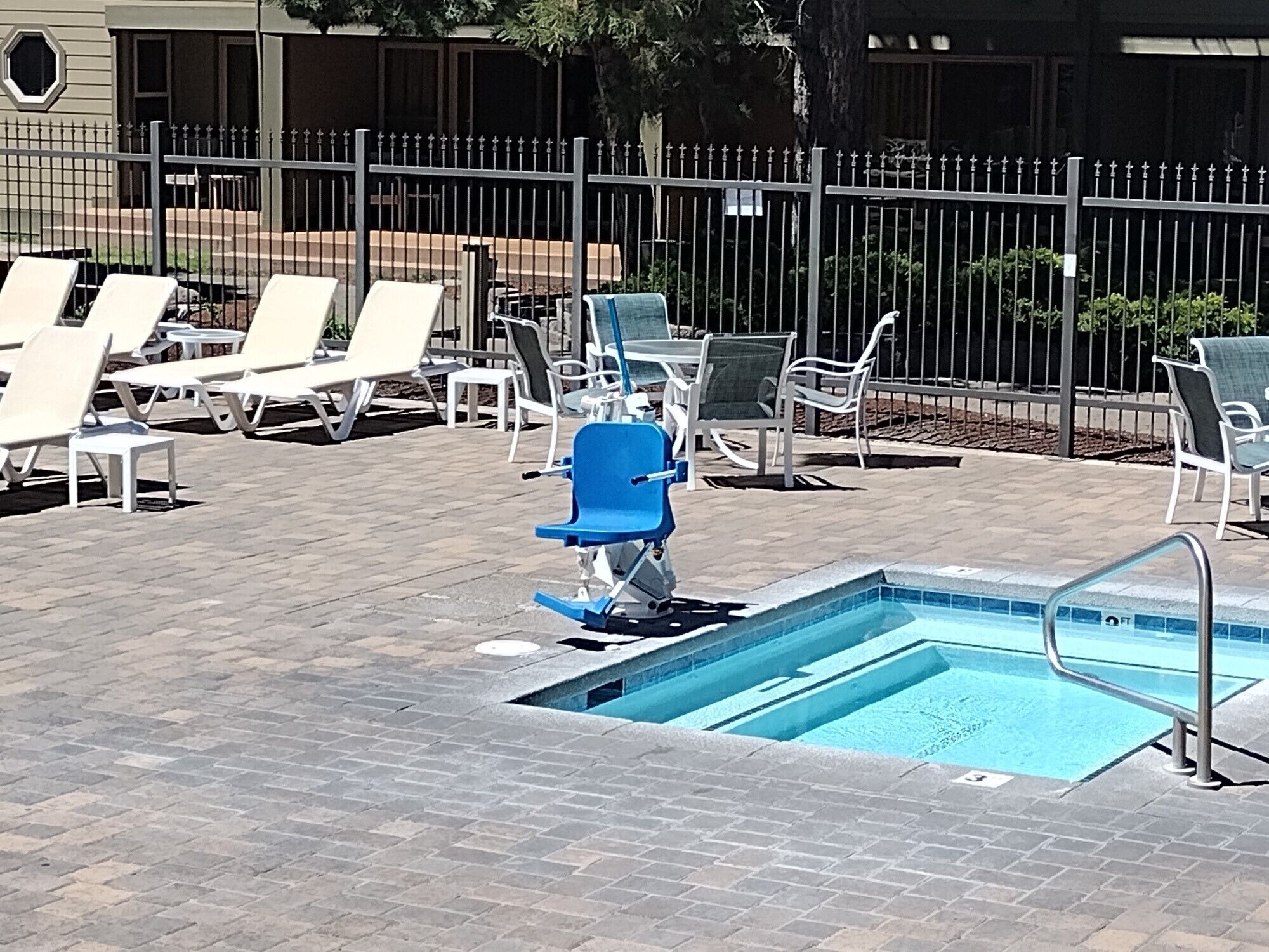 Uma área de piscina com cadeiras de sol e uma cadeira azul.