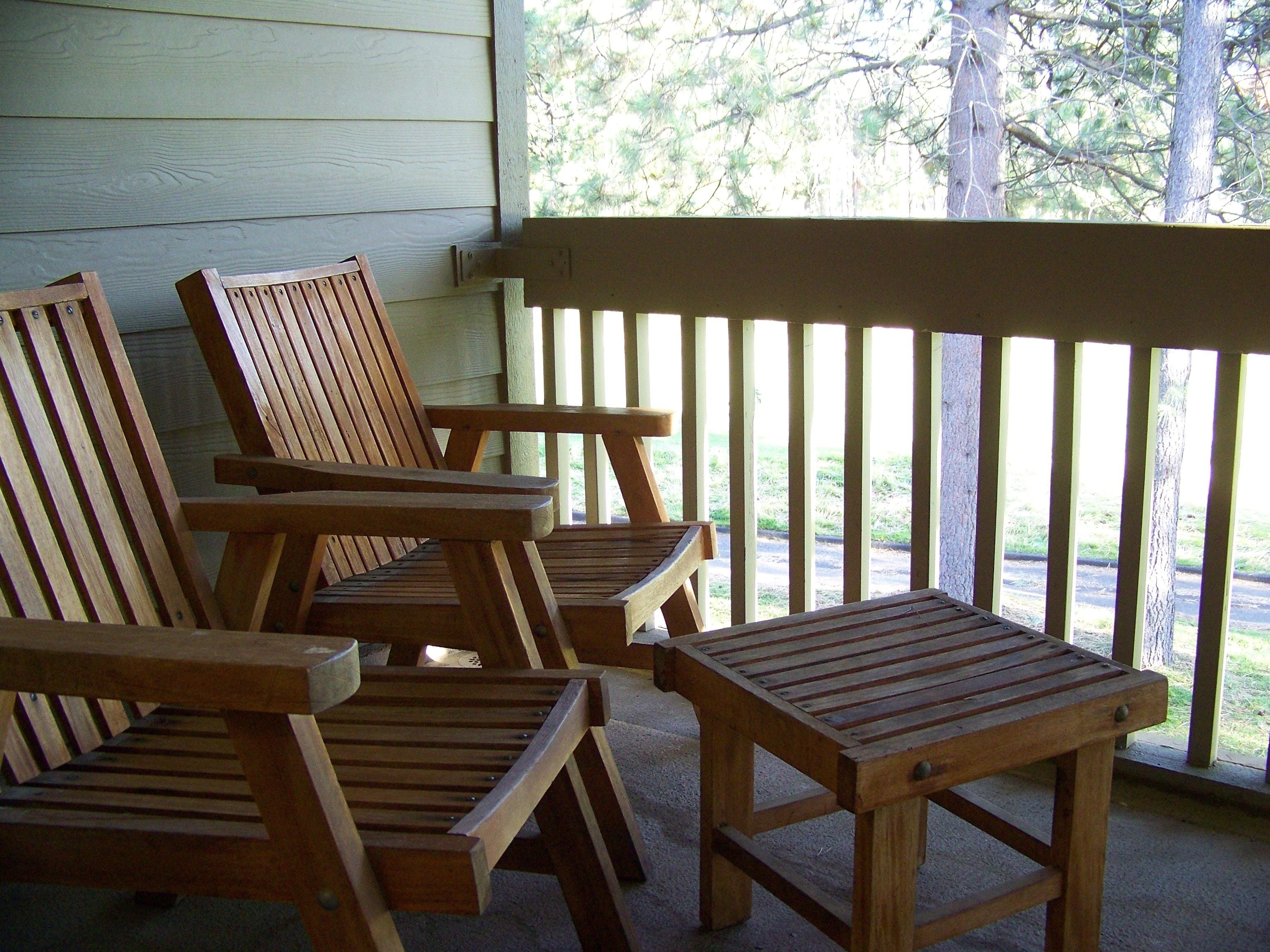 A wooden porch with three chairs and a small table.