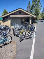 A bicycle parking area with multiple bicycles lined up in front of a building.
