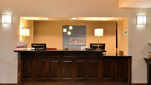 Un comptoir d’accueil avec un revêtement en bois, deux lampes, une enseigne « Holiday Inn Express » et un petit comptoir muni d’une caisse enregistreuse.