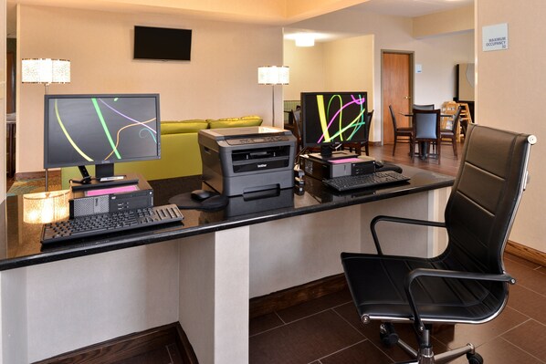 A hotel reception desk with two monitors, a printer, a keyboard, and a black office chair. - Holiday Inn Express & Suites St Marys by IHG (St. Marys)