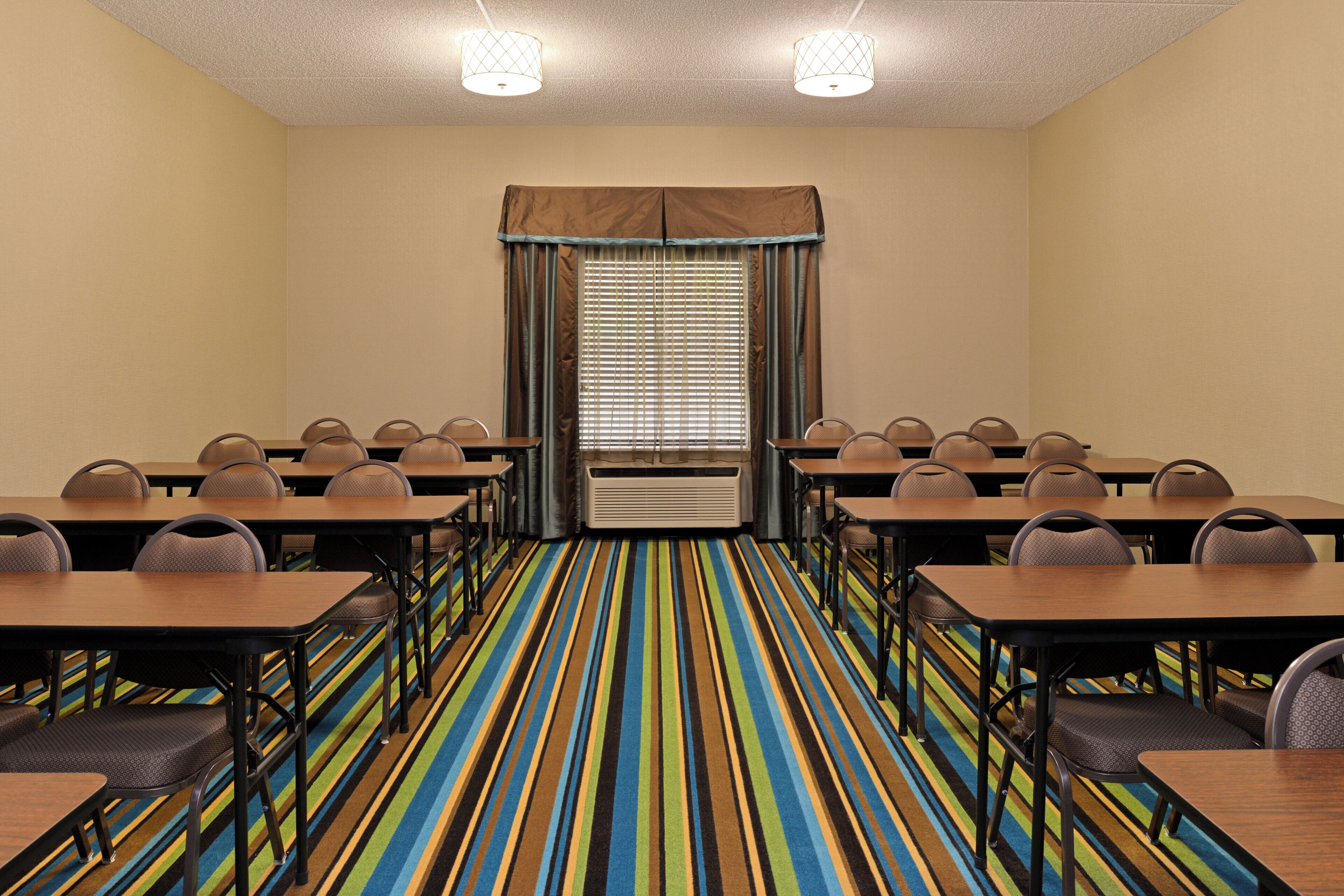 A conference room with a striped carpet, multiple tables, and chairs arranged for meetings.