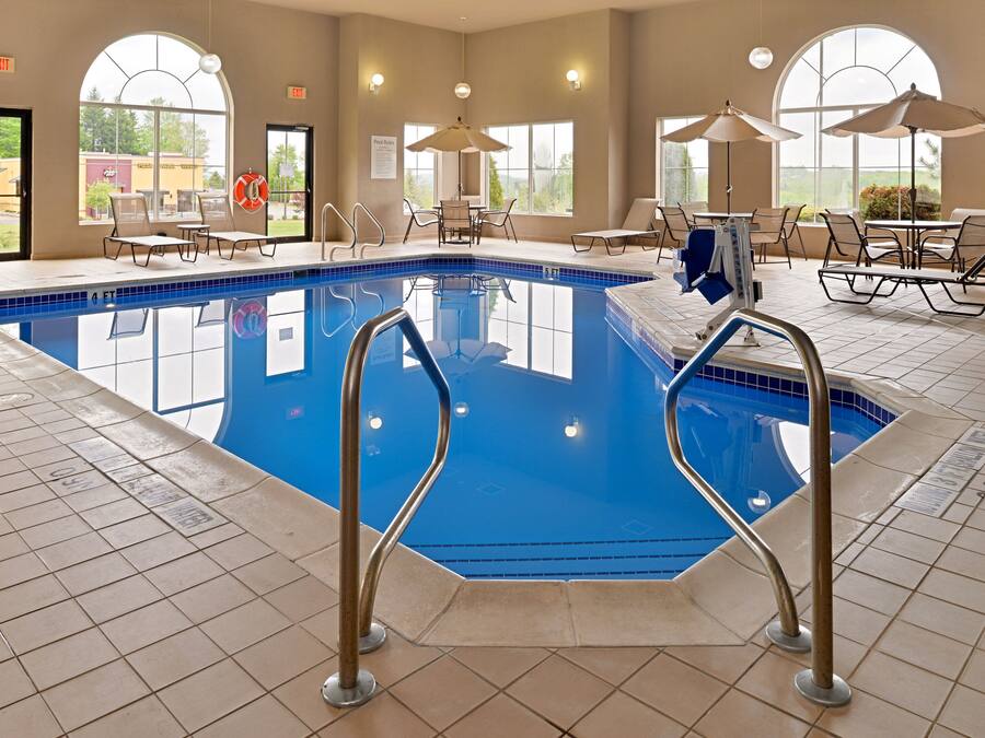 Una piscina interior con zonas de piscina despejadas, tumbonas y sombrillas.