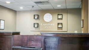 A reception area with a sign reading "Comfort Inn" and a wooden panel design. - Comfort Inn & Suites Fuquay Varina (Fuquay-Varina)