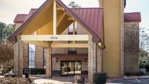 A hotel with a distinctive triangular roof structure, a brick facade, and a large entrance with glass doors. - Comfort Inn & Suites Fuquay Varina (Fuquay-Varina)