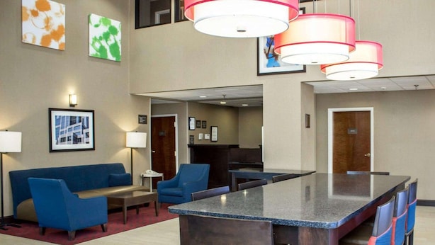 A hotel lobby with a reception desk, blue seating area, and a bar with a granite countertop. - Comfort Inn & Suites Fuquay Varina (Fuquay-Varina)