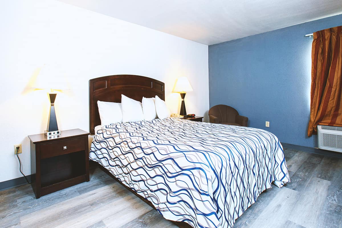 A bedroom with a bed, nightstands, and a wall-mounted heater.