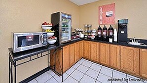 A kitchenette with a microwave, bowls of fruit, a refrigerator, and a coffee station.
