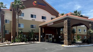 A Comfort Suites hotel with a covered entrance, palm trees, and a clear sky. - Comfort Suites Peoria Sports Complex (Peoria)