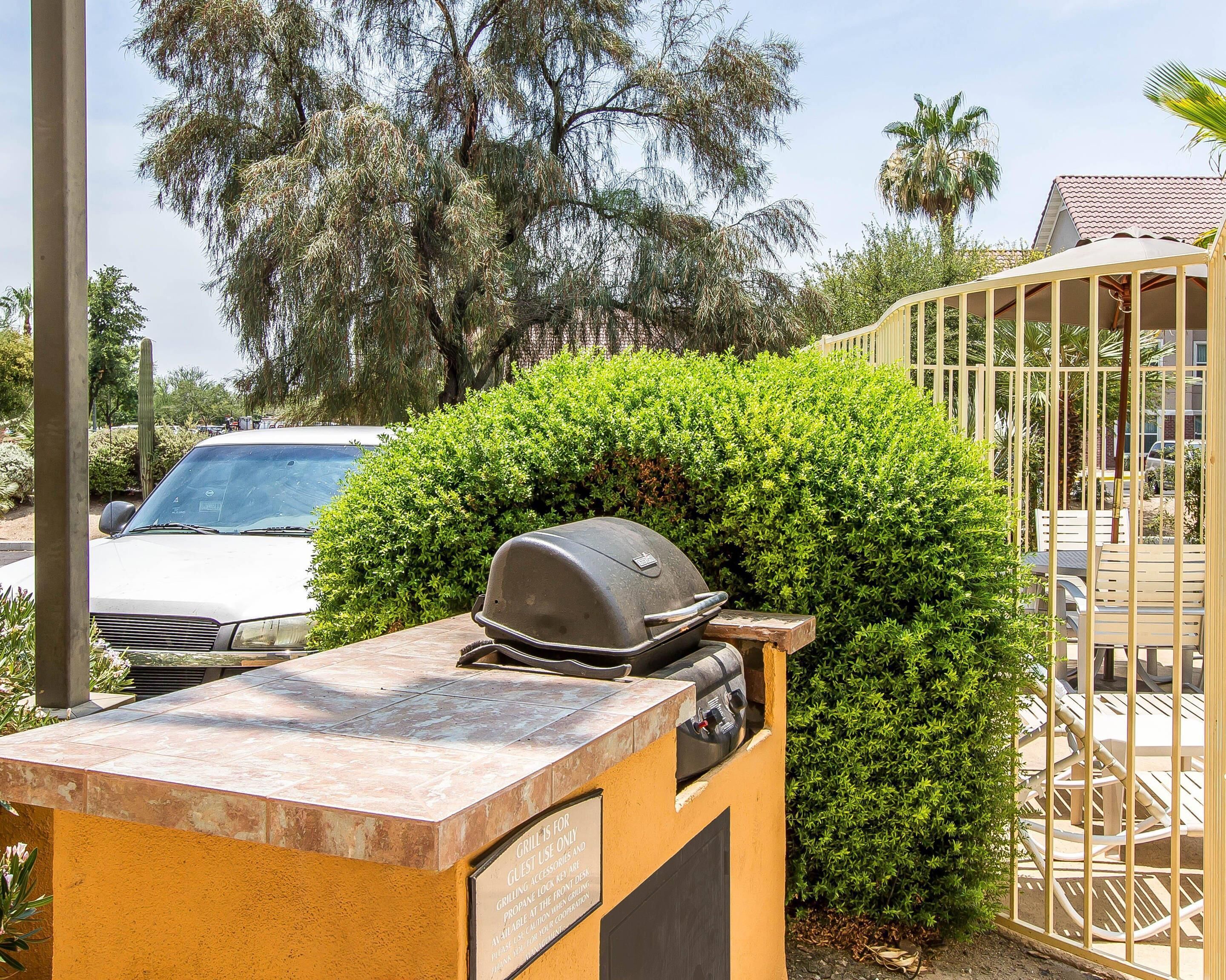 Eine Terrasse mit Grill, einem Auto und einem Tor.