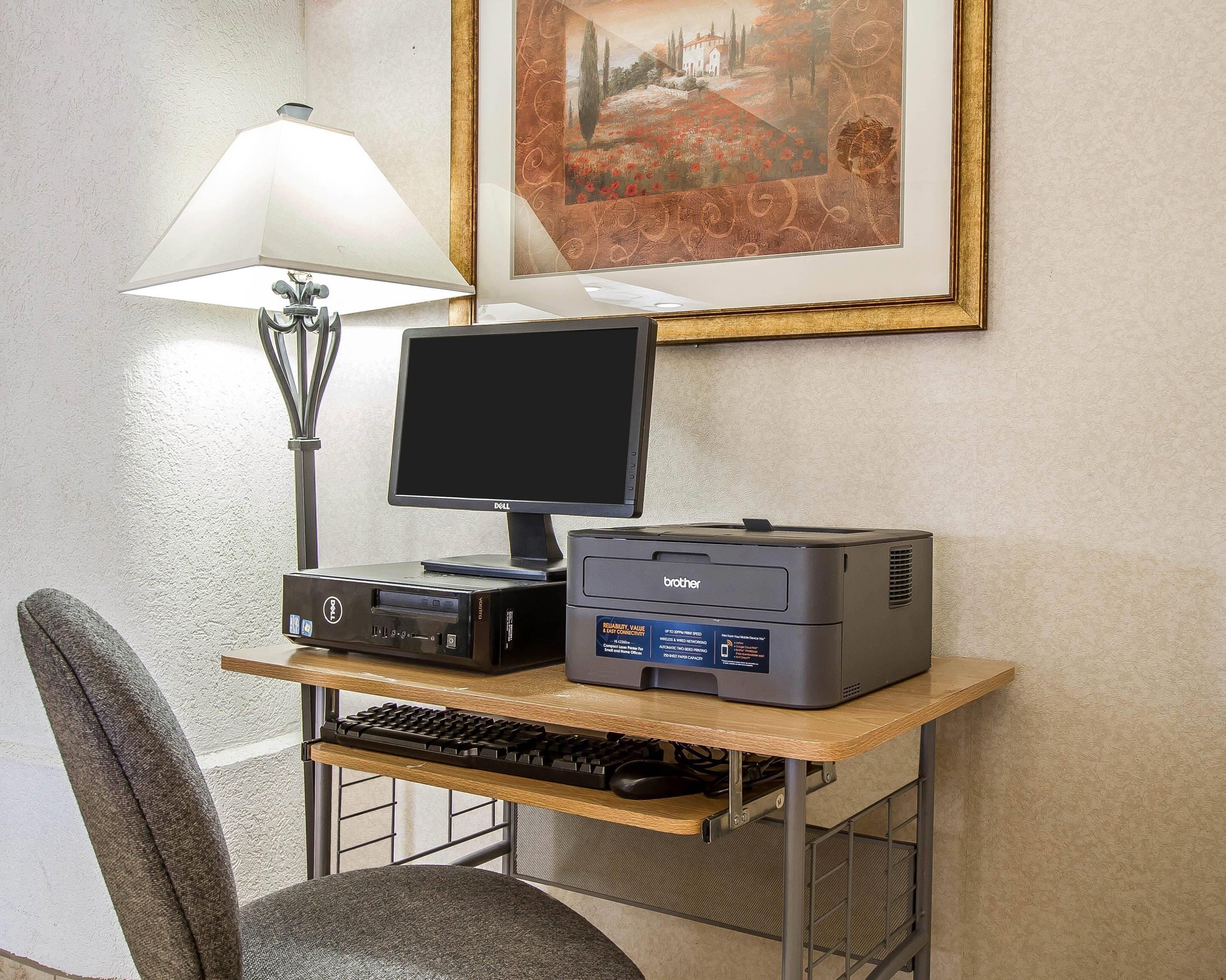Un bureau d’ordinateur équipé d’un écran, d’un clavier, d’une imprimante et d’une lampe.