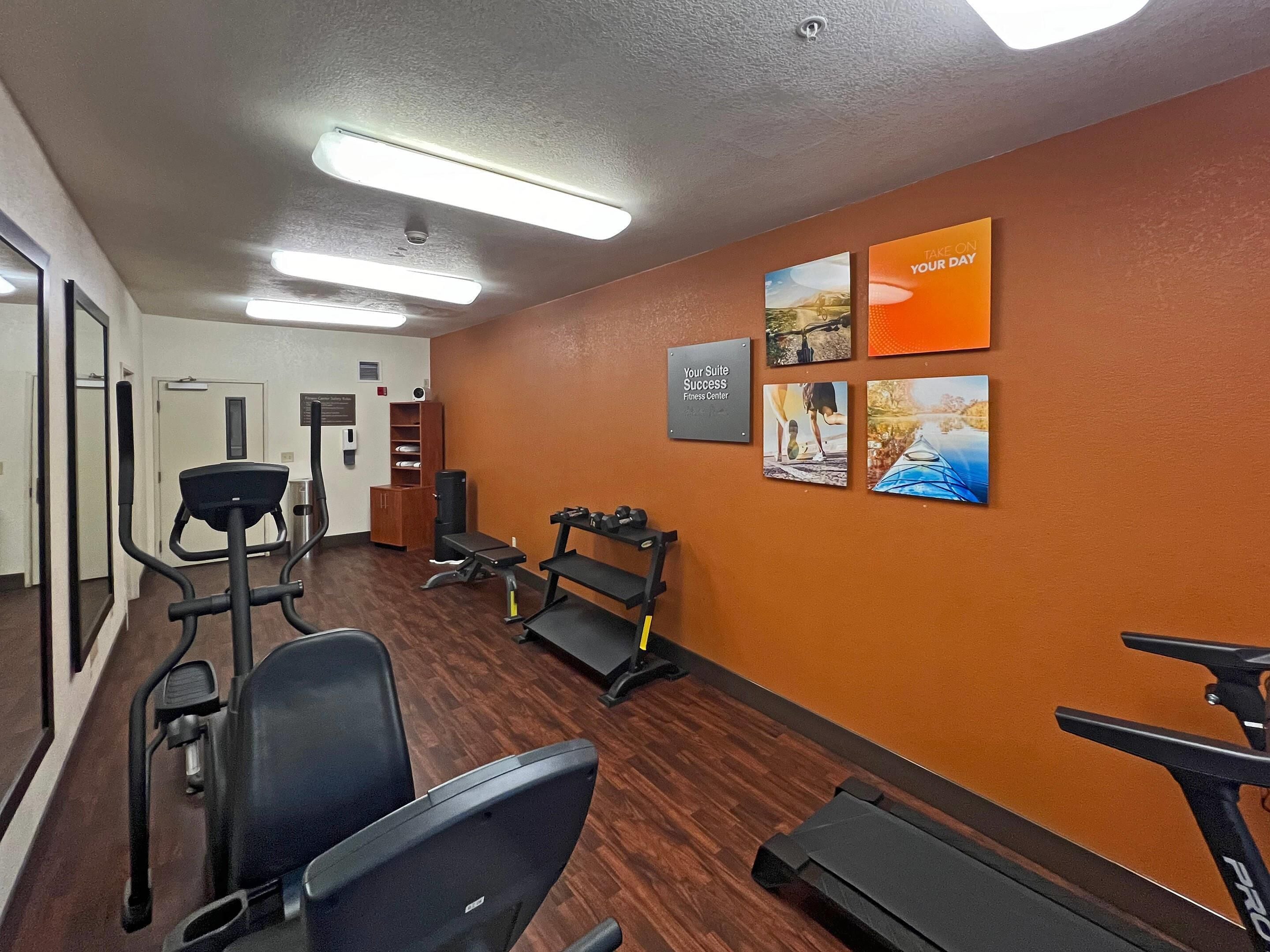 A fitness center with exercise equipment, a mirrored wall, and motivational posters.