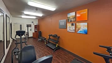 A fitness center with exercise equipment, a mirrored wall, and motivational posters.