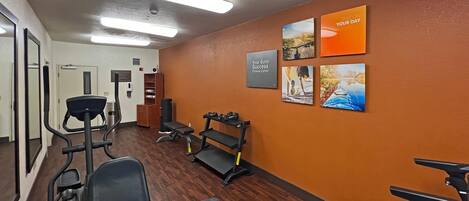 A fitness center with exercise equipment, a mirrored wall, and motivational posters.