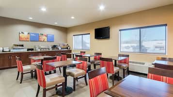 A restaurant with multiple tables and chairs, a kitchen area, and a large window providing a view of the outside.