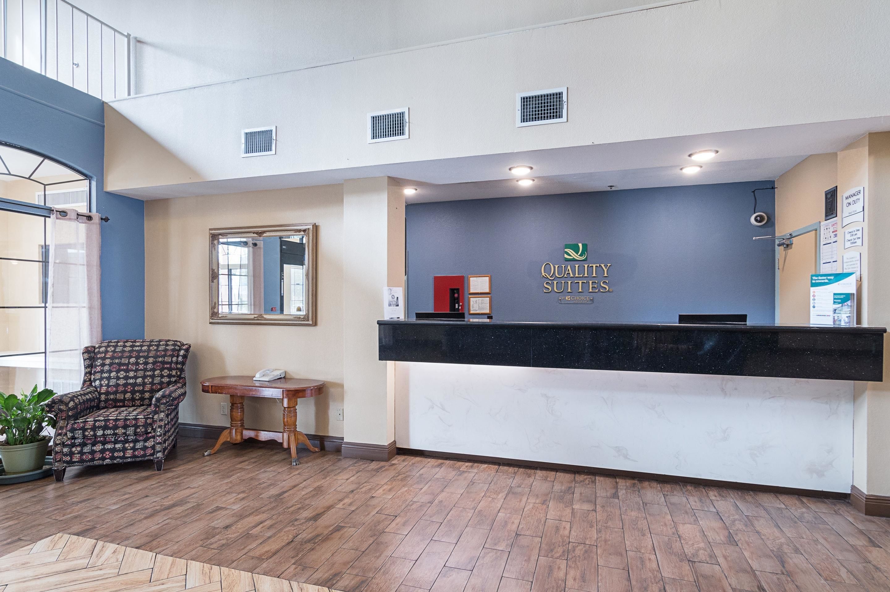 A reception area with a reception desk, a chair, a small table, and a potted plant.