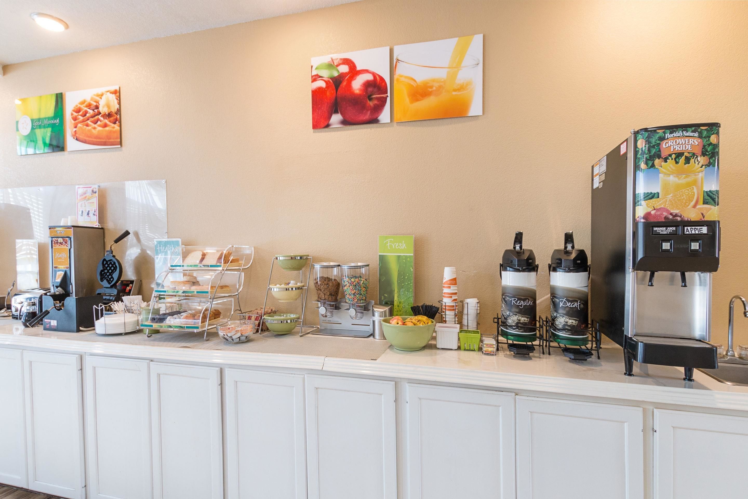 Un comptoir-buffet pour le petit-déjeuner, avec des machines à café, un distributeur de jus de fruits et un réfrigérateur.
