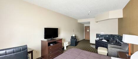 A hotel room with a bed, a TV, a desk, a chair, and a bathroom with a bathtub.