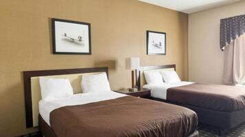 A hotel room with two beds, each with white and brown bedding. There are framed pictures on the wall above the beds.