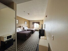 Habitación de hotel con dos camas, un escritorio, un microondas y una ventana con cortinas.