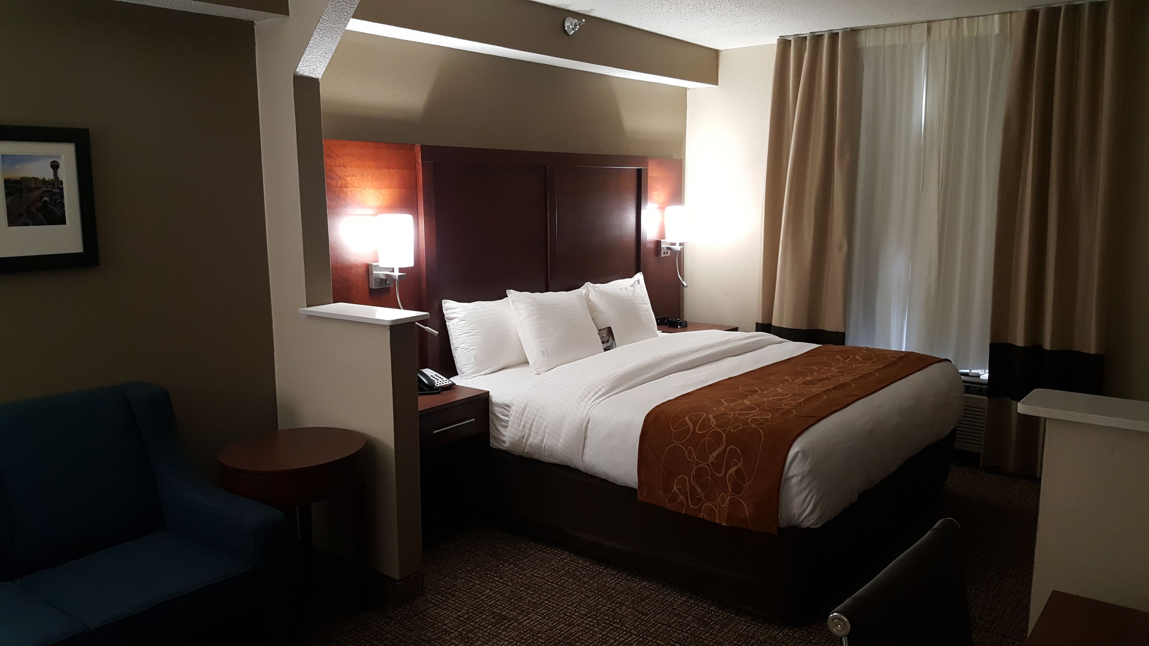Une chambre d’hôtel comprenant un lit, des tables de chevet, un bureau, une chaise et une lampe.