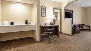 Une chambre d’hôtel équipée d’un bureau, d’une chaise et d’un téléviseur fixé au mur.