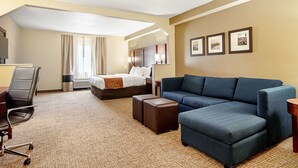 Une chambre d’hôtel avec un lit, un canapé bleu, un bureau avec une chaise et une petite table.