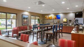 A restaurant with booths and tables, a kitchen area, and large windows. - Comfort Inn & Suites Peachtree Corners - Norcross (Norcross)