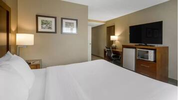 A hotel room with a large bed, a television, a microwave, and two framed pictures on the wall.