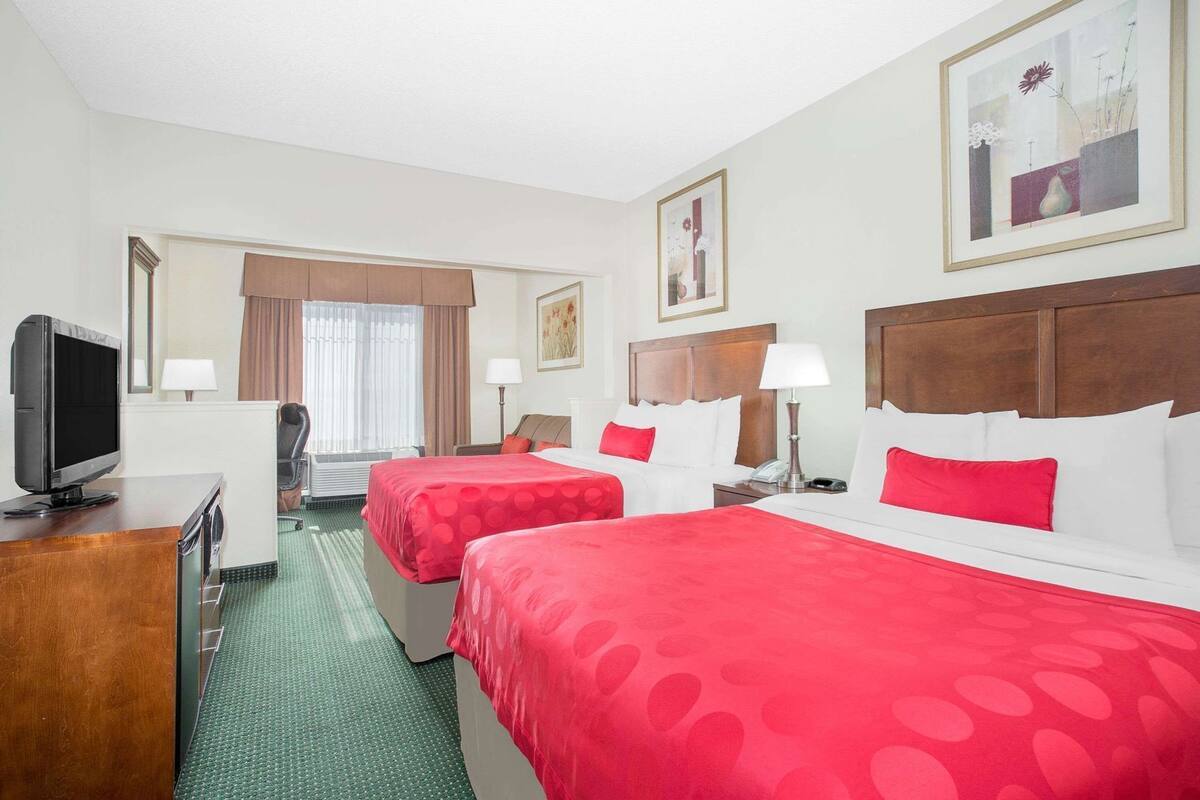 Een hotelkamer met twee bedden, een televisie, een bureau en een raam met gordijnen.