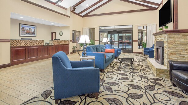 A spacious lobby with a reception desk, seating area, and a fireplace. - Ramada by Wyndham Denver International Airport (Denver)