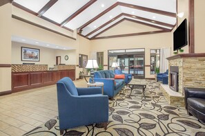 A spacious lobby with a reception desk, seating area, and a fireplace. - Ramada by Wyndham Denver International Airport (Denver)