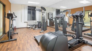 A gym with exercise equipment, wooden flooring, and a large mirror. - Ramada by Wyndham Denver International Airport (Denver)