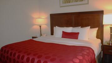Una habitación de hotel con una cama grande, dos mesitas de noche y una mesilla auxiliar con lámpara.