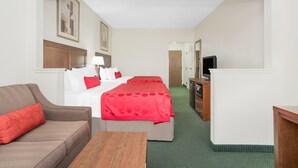A hotel room with a bed, a sofa, a TV, and a desk. - Ramada by Wyndham Denver International Airport (Denver)
