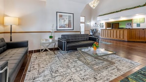 A hotel lobby with a reception desk, a sofa, a coffee table, and a chandelier. - Quality Inn & Suites Stoughton - Madison South (Stoughton)