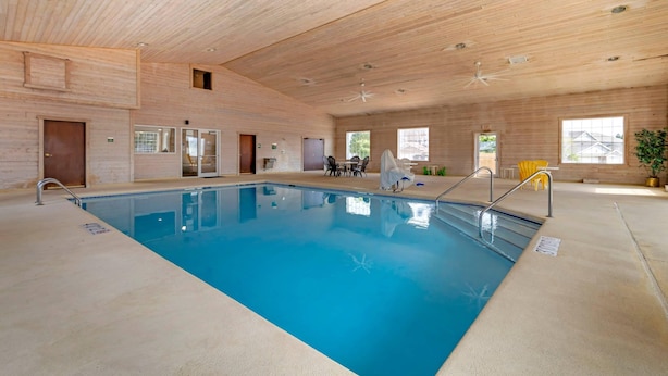 An indoor swimming pool with a wooden ceiling, a ceiling fan, and a seating area with chairs. - Quality Inn & Suites Stoughton - Madison South (Stoughton)