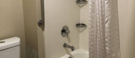 Une salle de bain équipée de toilettes, d’une douche avec rideau et d’une barre d’appui.