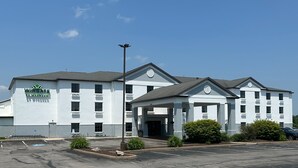 A multi-story hotel with a modern design, featuring a prominent entrance with a covered area and a parking lot in front.