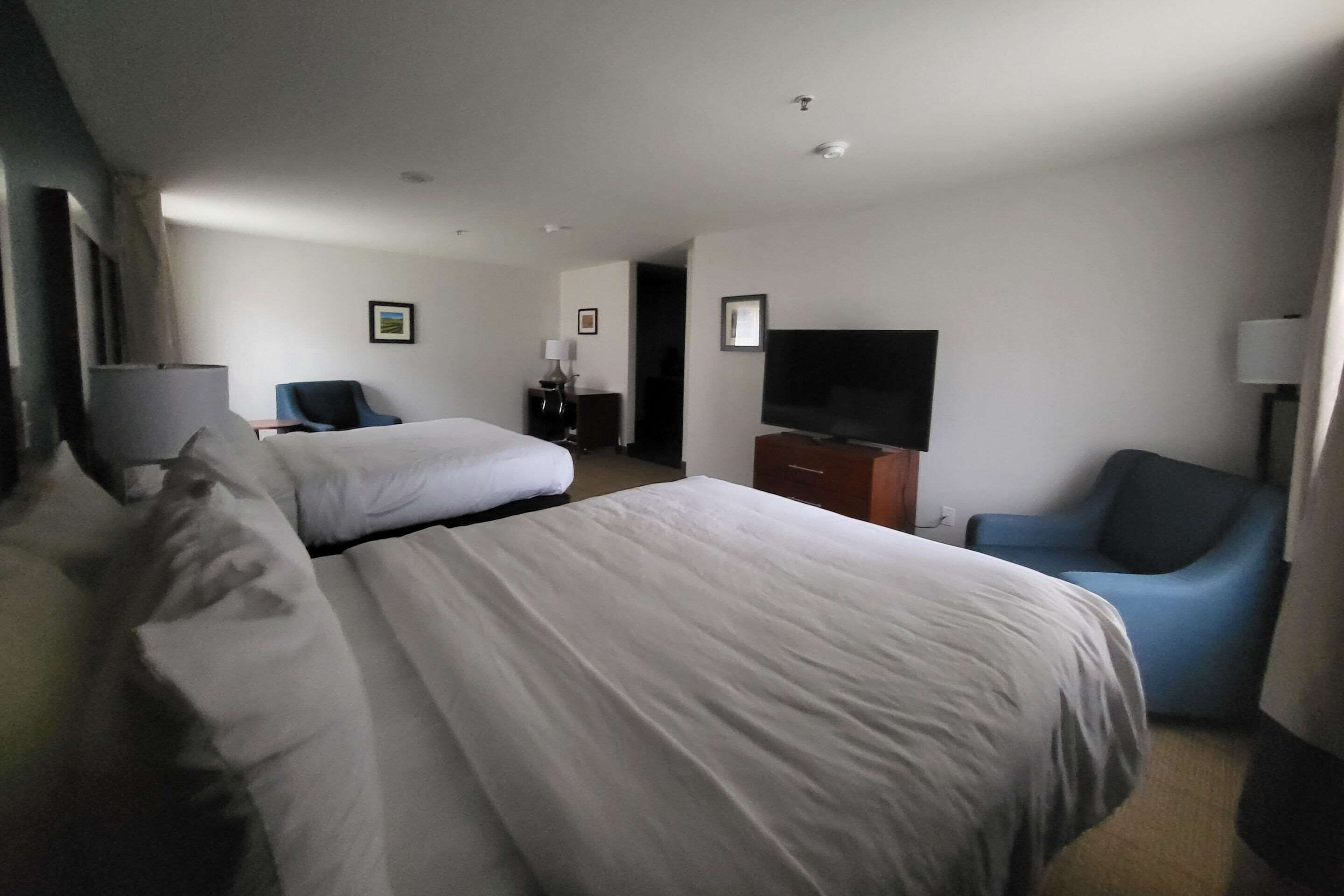 Habitación de hotel con dos camas, televisión, escritorio y una silla.