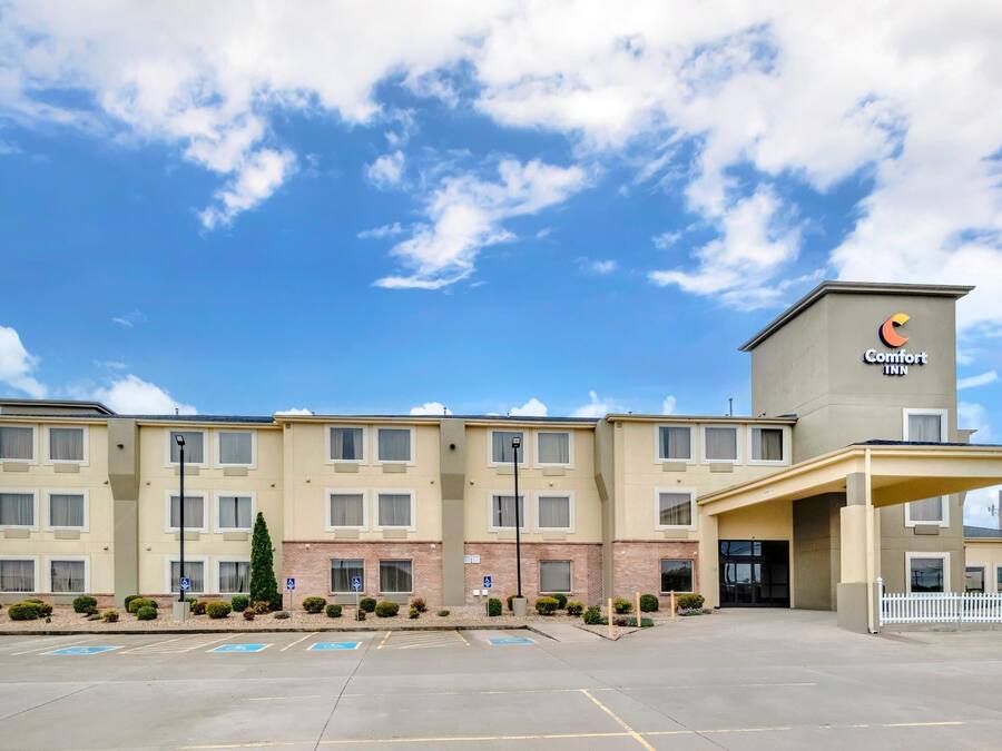 Comfort Inn -hotelli, jossa on pysäköintialue, katettu sisäänkäynti ja kirkas, sininen taivas.