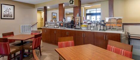 A restaurant with wooden tables and chairs, a counter with coffee machines, and a clock on the wall.