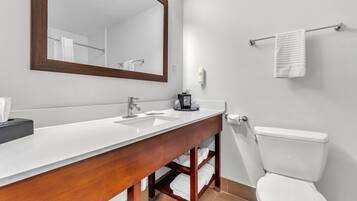 Un baño moderno con tocador de madera, un espejo grande, un inodoro blanco y un perchero para toallas.