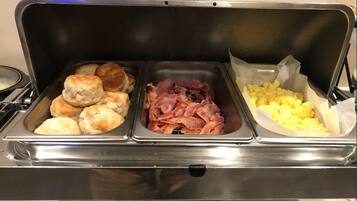 A buffet with three food stations: biscuits, bacon, and scrambled eggs.