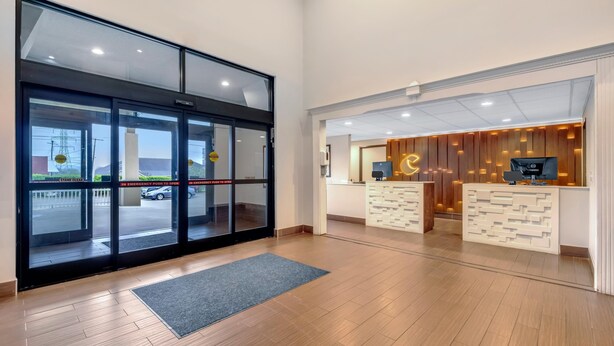 A hotel reception area with a modern design, featuring a reception desk, a computer, and a large glass door leading outside. - Comfort Inn Somerset - Lake Cumberland (Somerset)