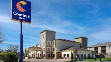Ett Comfort Inn-hotell med en väl synlig skylt, en parkeringsplats och en byggnad med flera våningar och balkonger.